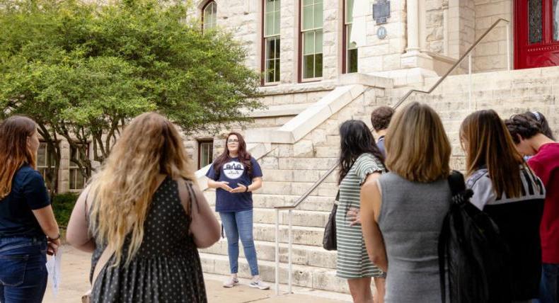 Campus Tour Guide speaks to visitors in front of Main Building